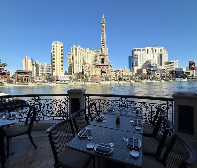 An outdoor dining table on a boat deck overlooking the Las Vegas skyline and Lake Las Vegas, with the replica Eiffel Tower in view